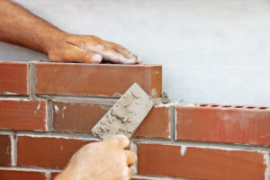 Man laying bricks on a new house