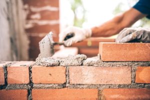 delprete masonry a man placing mortar down on as he builds a brick wall